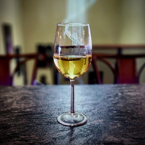 A glass of white wine sits on a dark, textured table at Portofino's Italian restaurant.