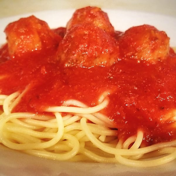Spaghetti with meatballs and rich red marinara sauce on a white plate, ready to be served.