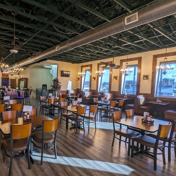 Spacious dining room at Portofino's with tables, chairs, booths, and a bar area under a dark ceiling.